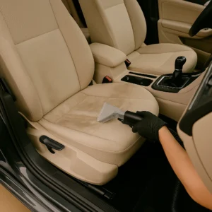 Professionele reiniging van een beige autostoel met bekledingsextractiemachine.