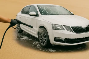 Close up van een witte sedan die wordt afgespoten met een hogedrukreiniger tijdens een wasbeurt.